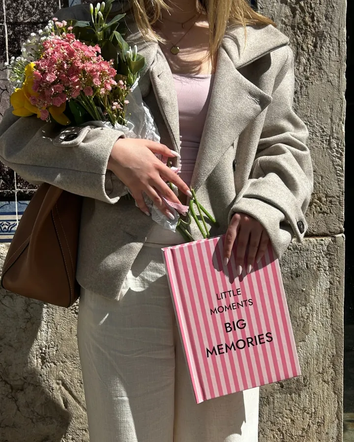 Cliente com o álbum Little Moments Big Memories e um ramo de flores